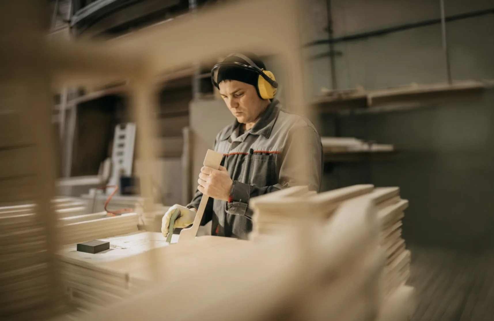 Carpintero de Silverwood lijando una pieza de madera entre tableros apilados en el taller